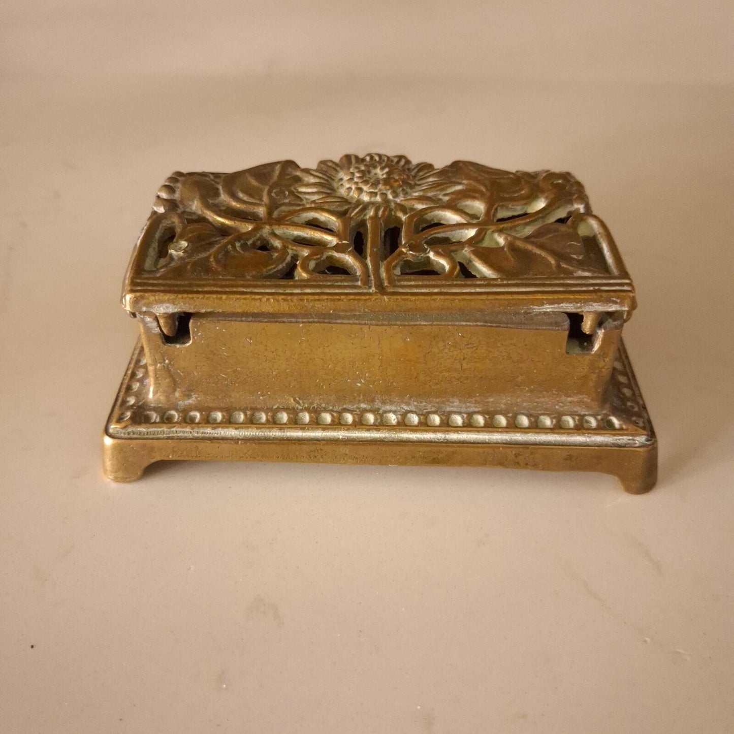 A brass sunflower design brass stamp holder