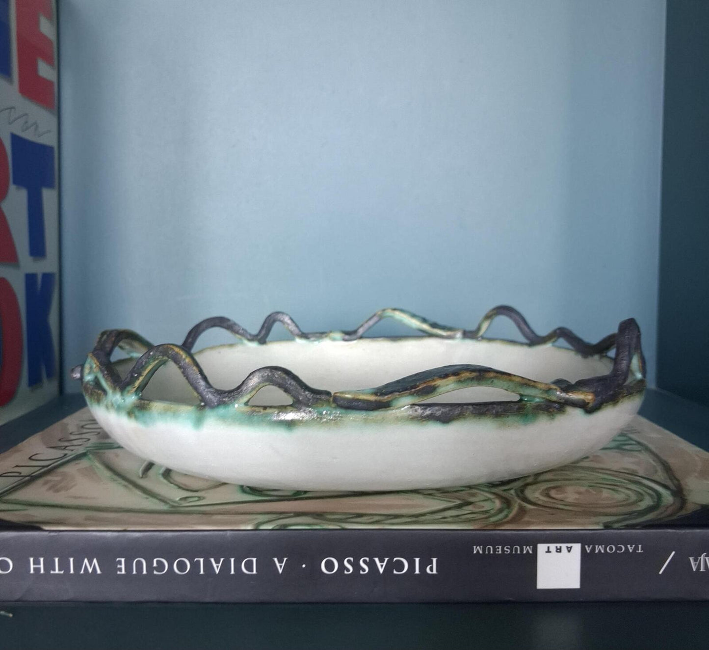 A decorative studio pottery shallow glazed bowl with fish and wave detailed rim