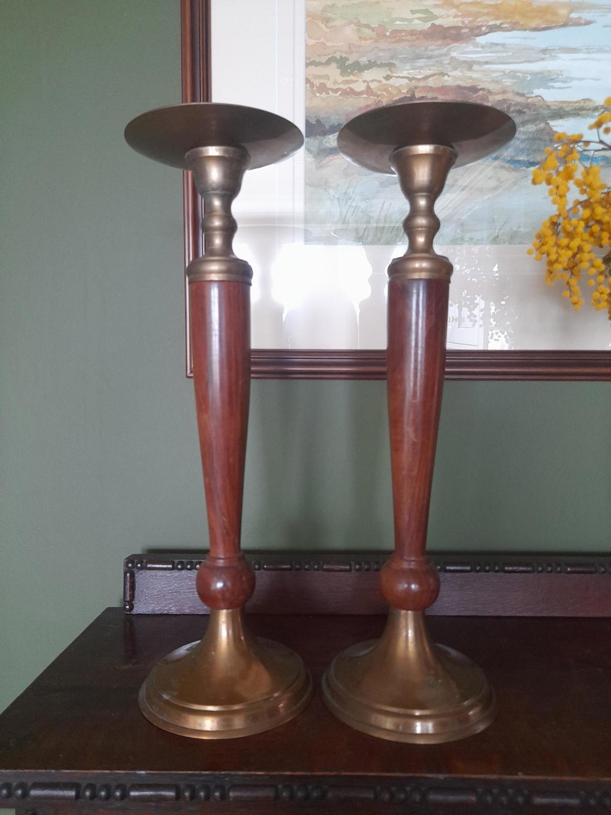 A pair of brass and dark wood tall candle holders