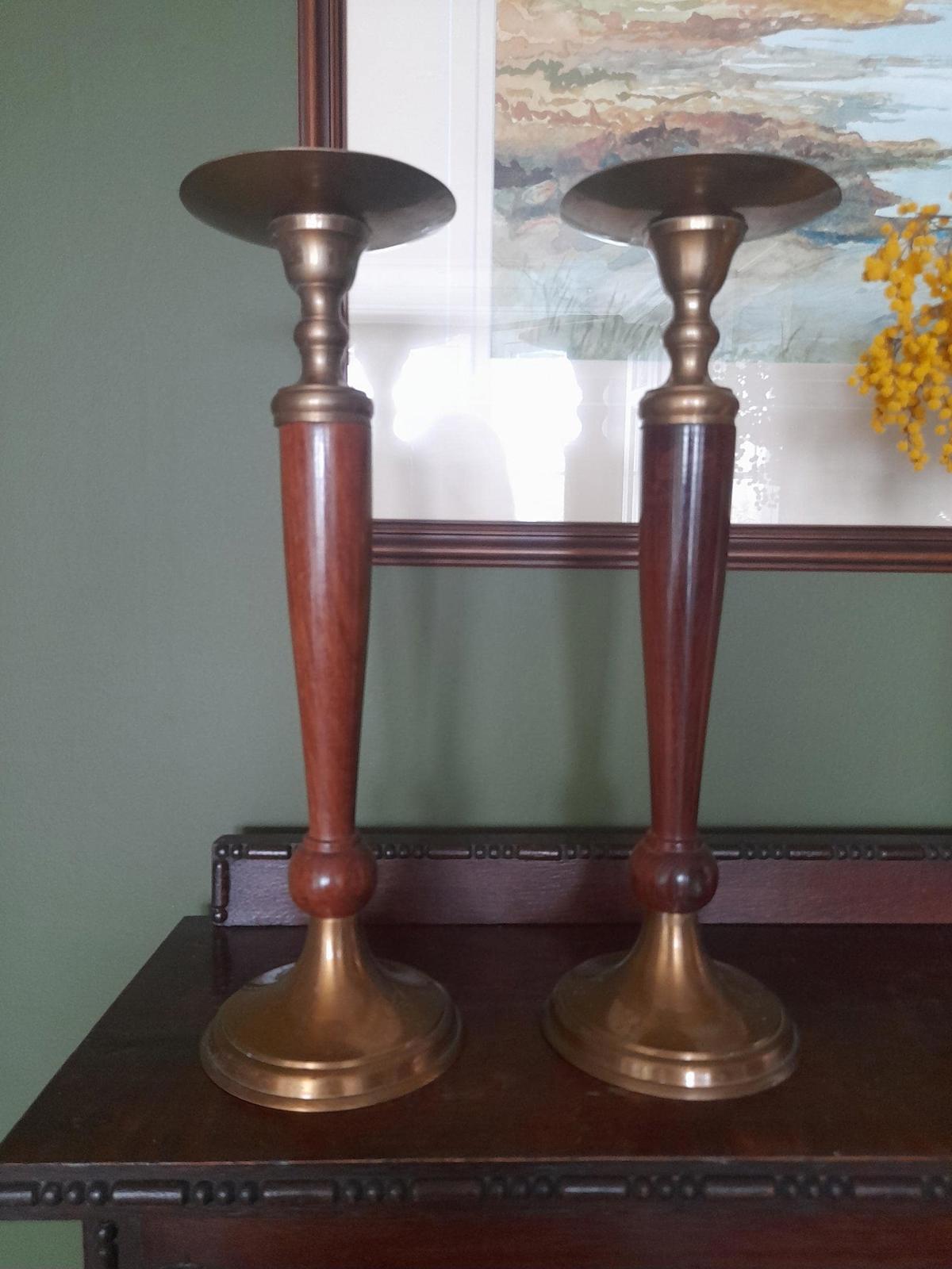 A pair of brass and dark wood tall candle holders