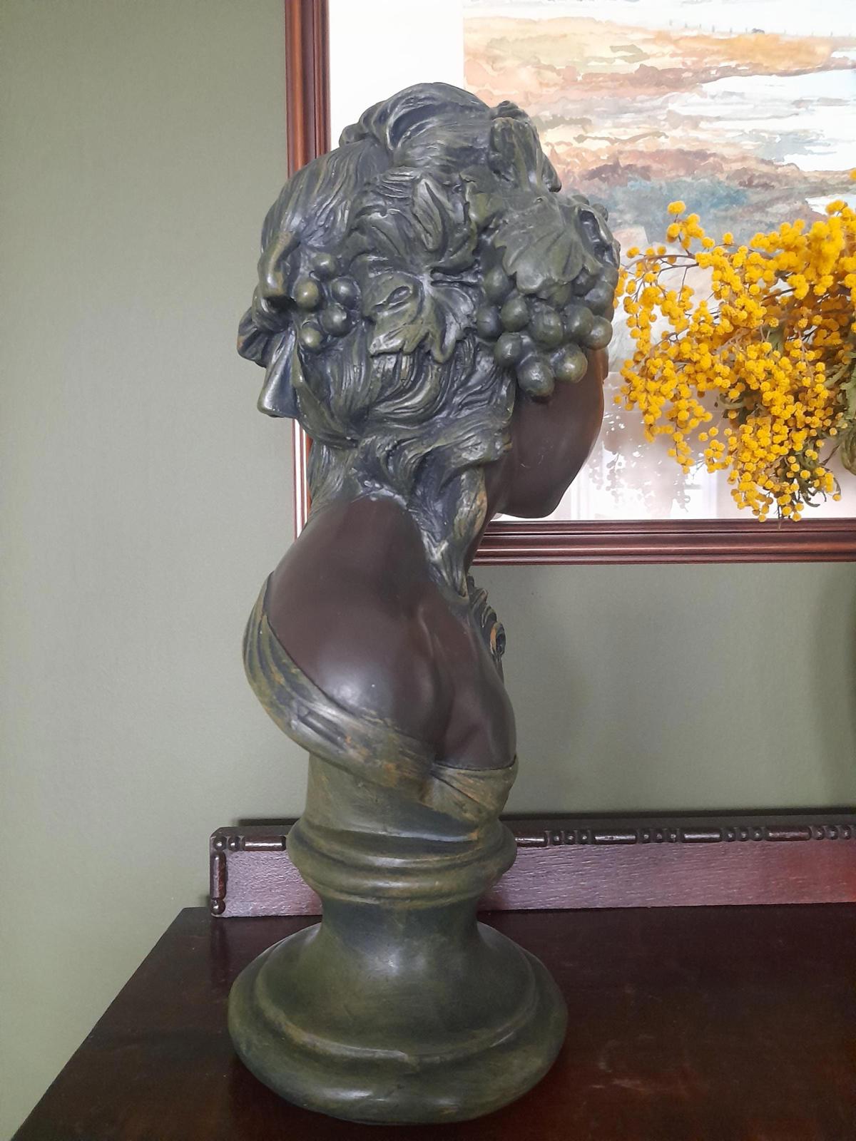 Plaster bust and shoulders of a young woman.