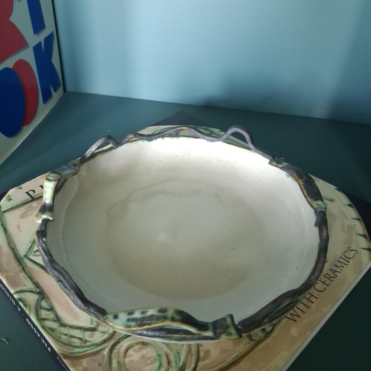 A decorative studio pottery shallow glazed bowl with fish and wave detailed rim