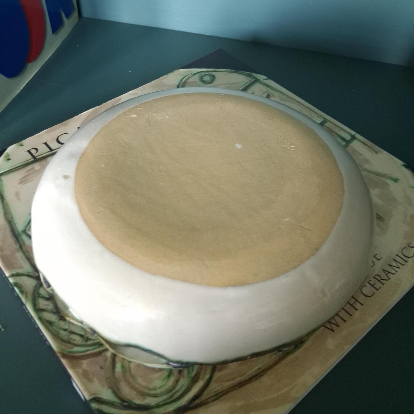 A decorative studio pottery shallow glazed bowl with fish and wave detailed rim