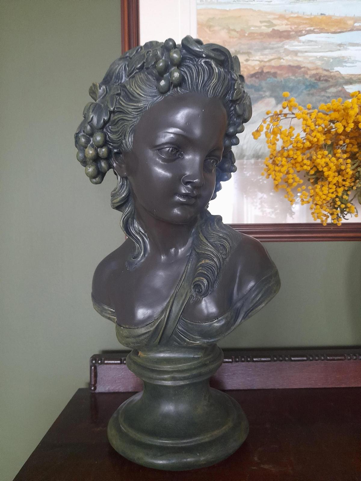 Plaster bust and shoulders of a young woman.