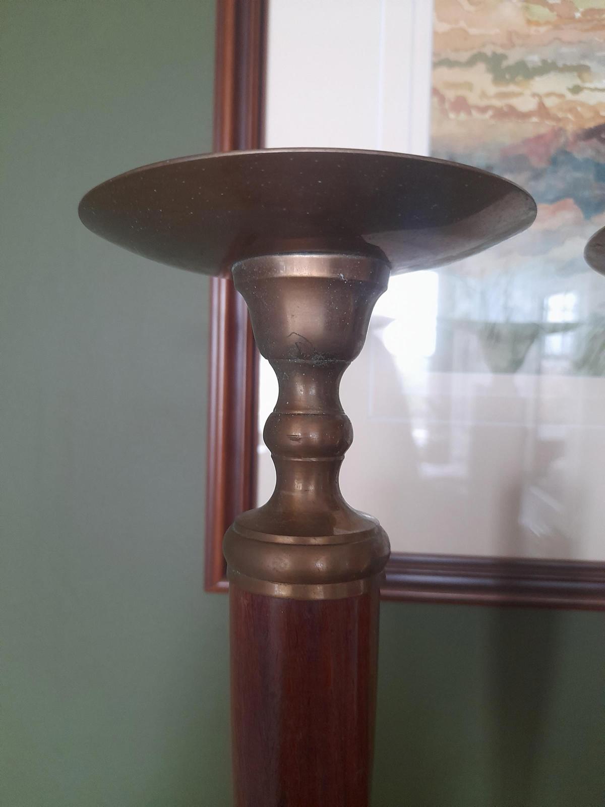 A pair of brass and dark wood tall candle holders