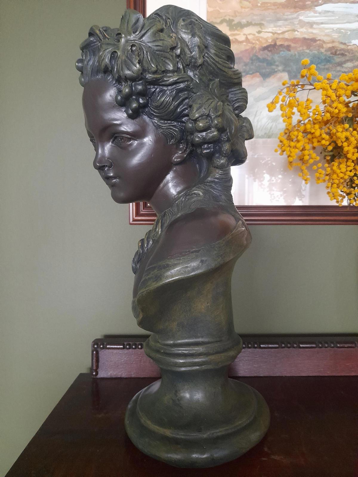 Plaster bust and shoulders of a young woman.