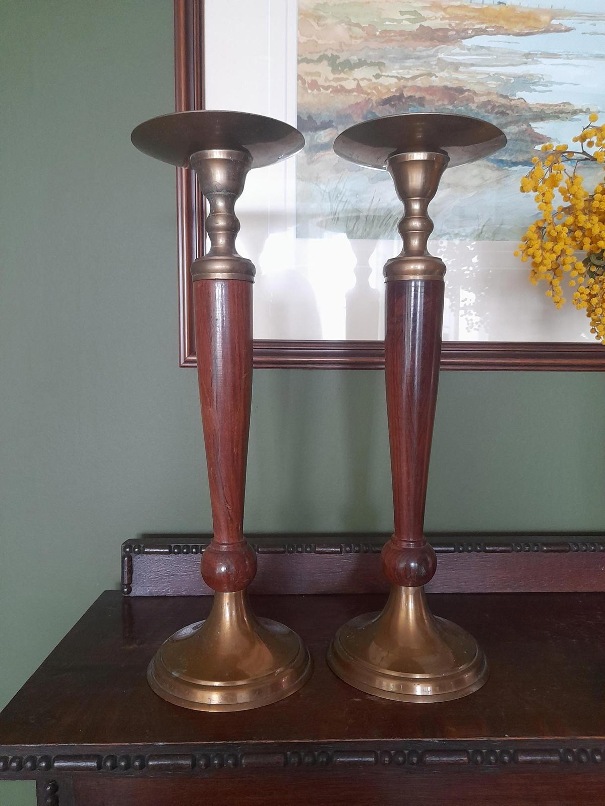 A pair of brass and dark wood tall candle holders