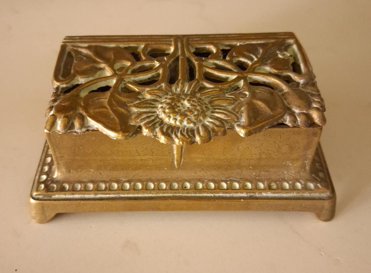 A brass sunflower design brass stamp holder