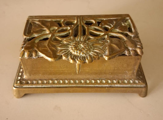 A brass sunflower design brass stamp holder